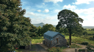 The view of the Copper Barn from the country road above, on a glorious summer's day with Slemish standing proudly on the horizon. This can be your home on our guided hiking holidays