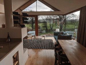 The lines of the corian worksurface on the kitchen island, the edge of the hand-made dining table and the tops of the windows all draw your eye out to those 270 degree views, meaning that you always feel close to nature in the Copper Barn