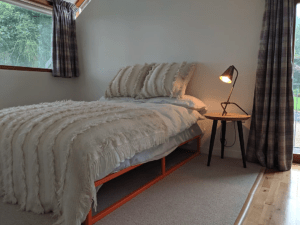 The striking orange paint on the bespoke hand-made bed in the master bedroom provides a surprising but sympathetic pop of colour among the Irish made woollen blankets and linen sheets
