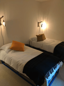 Reclaimed old industrial lamps help brighten the corners of the guest twin room and emphasis the bright colours of the Mourne Textile cushions